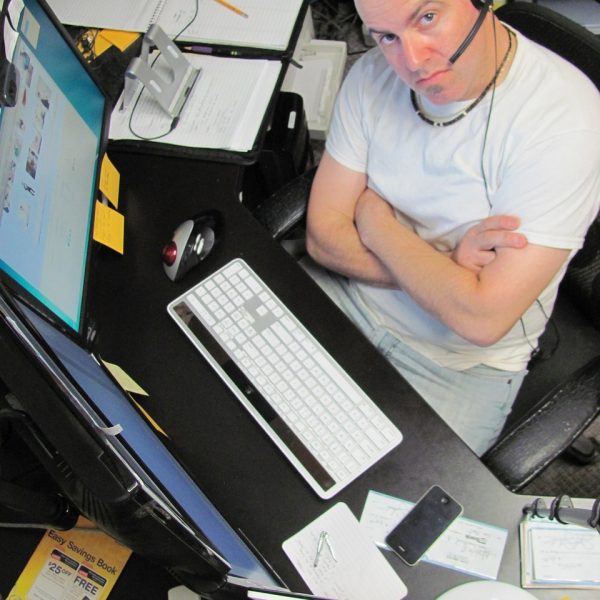 mężczyzna przed komputerami w pracy, hosting www, tworzenie stron